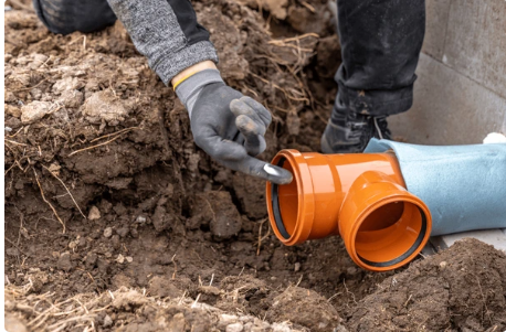 Titan Drain Services engineer in hi-vis repairing a damaged underground drainage pipe in an excavation